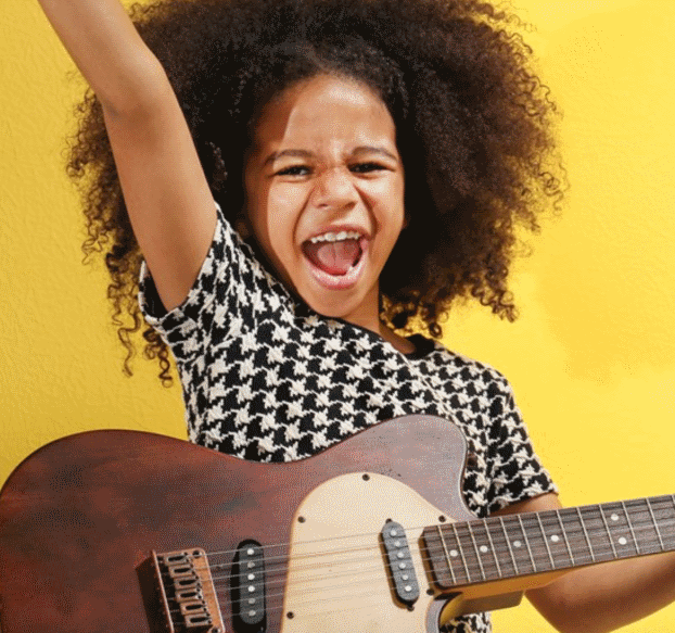 Young boy smiling while playing the guitar